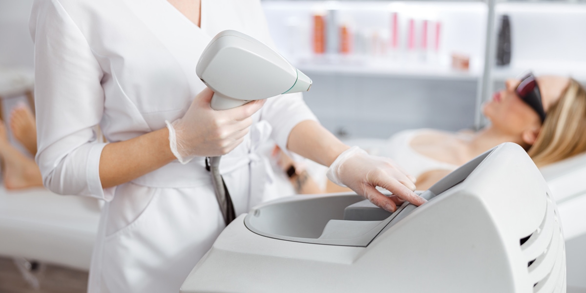 Woman beautician using laser epilation machine in beauty salon